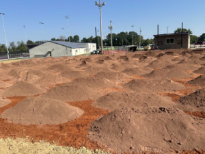 Baseball field renovation with dirt mounds and background buildings by Freeman Athletic Fields in Owensboro, KY