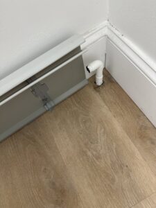 Close-up of a pipe connection to a baseboard heater, showing plumbing work by Clear Flow Plumbing, Heating, and Hvac Contractors LLC in Jersey City, NJ