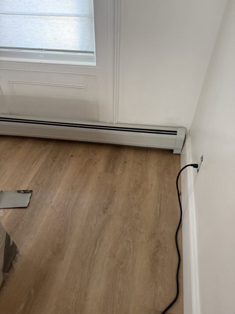 New baseboard heating unit installed along a wall with light wood flooring by Clear Flow Plumbing, Heating, and Hvac Contractors LLC in Jersey City, NJ