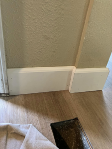 Baseboard trim installation in progress with tools on the floor, showing handyman finish work by JMY Construction in Meridian, ID.