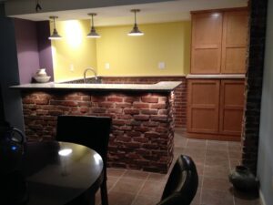 A custom-built basement bar with a brick facade and new cabinets by Constructed by 360 LLC in Meridian, ID.