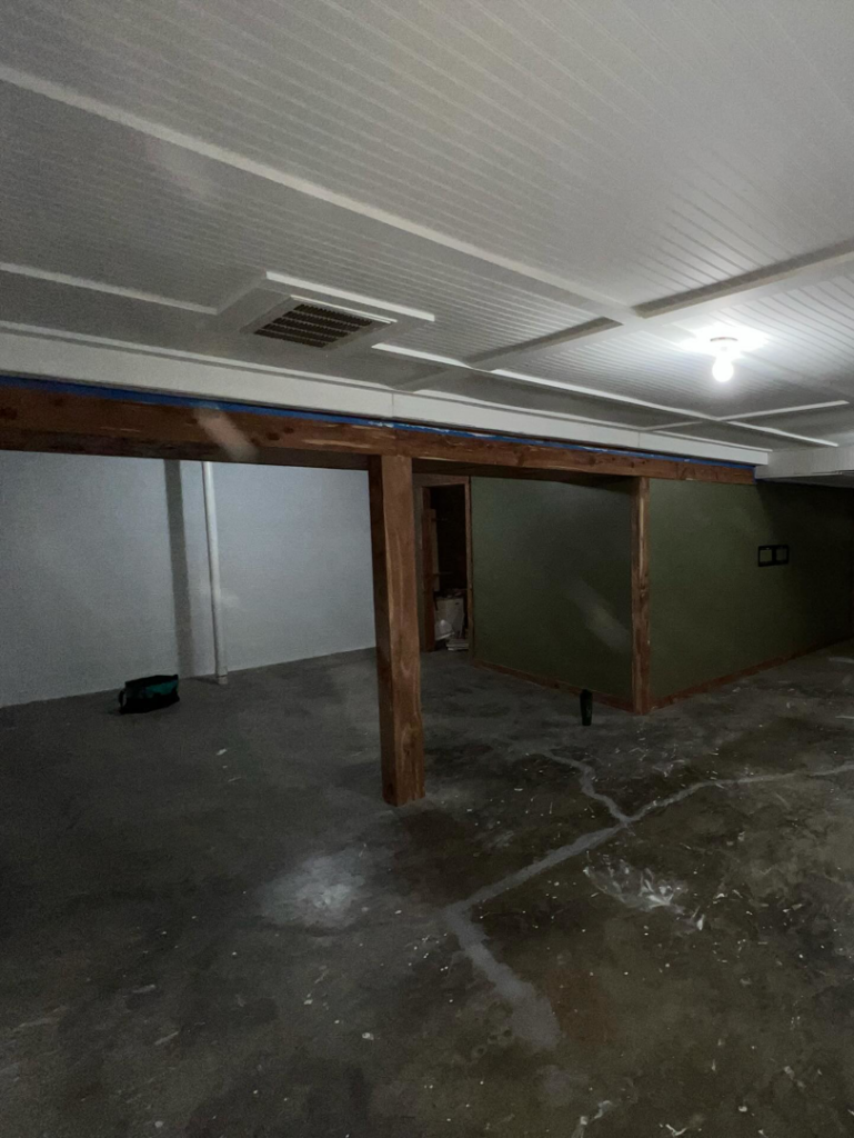 A basement renovation showing a new beadboard ceiling, wooden support beams, and wall framing by Kangas Contracting LLC in Chesapeake, VA.