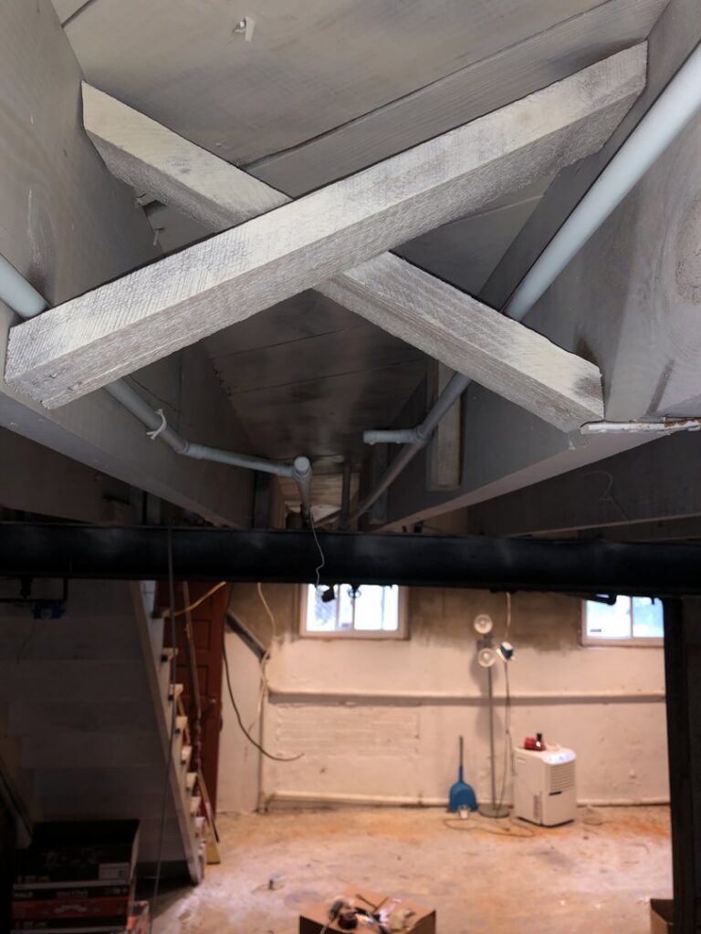 Exposed basement ceiling showing utility pipes and wiring during a renovation by AES Electrical Contractor in Richmond, VA.