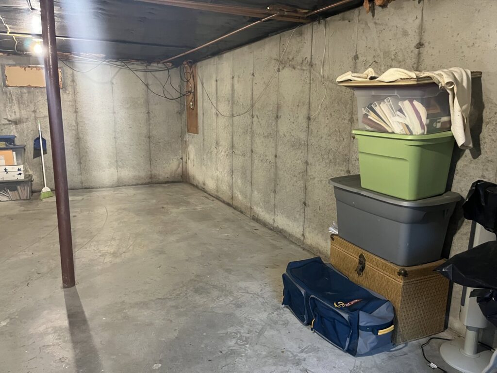 An unfinished basement with items stacked in a corner, ready for a cleanout service by Mr. Property Service in Sanford, ME.