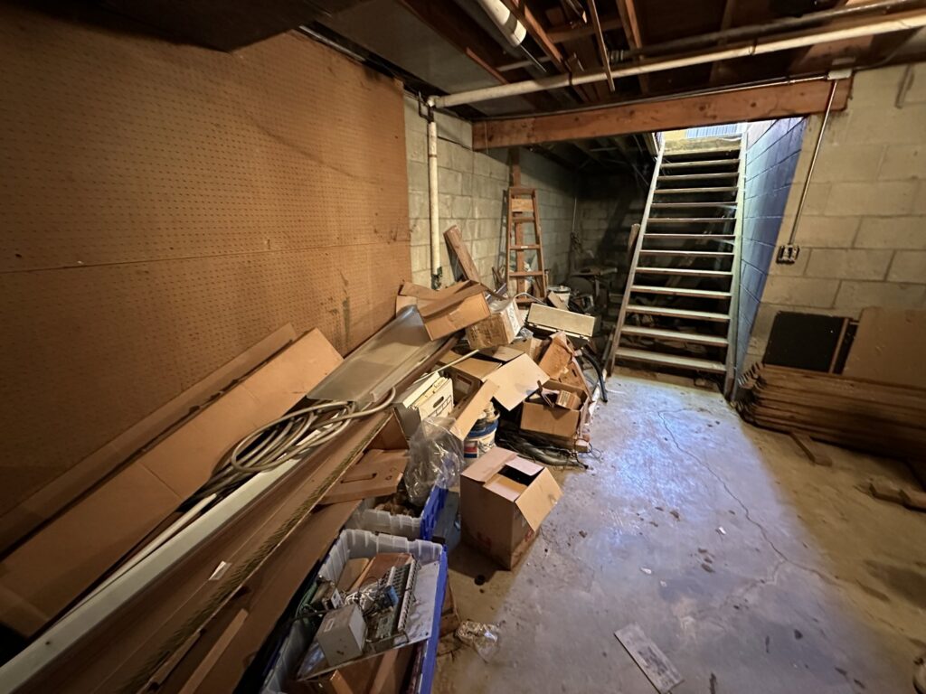 A basement area with boxes, metal pieces, and general clutter ready for debris removal by Vargas Junk Removal & Dumpster Rentals in Urbandale, IA.