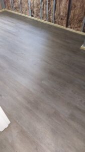 A basement under construction, showing wall insulation and new wood-look flooring installed by Impressive Basements in Westland, MI.