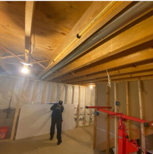 A worker installing drywall in a basement using a drywall lift, a service provided by Jarrett's Home Improvements & Maintenance Services in Columbus, OH
