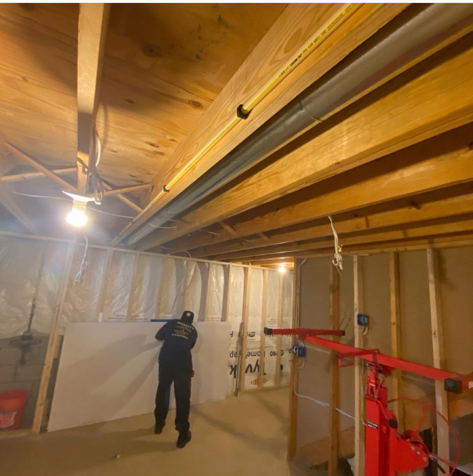 A worker installing drywall in a basement using a drywall lift, a service provided by Jarrett's Home Improvements & Maintenance Services in Columbus, OH