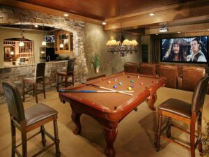 A finished basement entertainment room with a custom bar and stone work by Surfaces By Design in Duluth, MN.