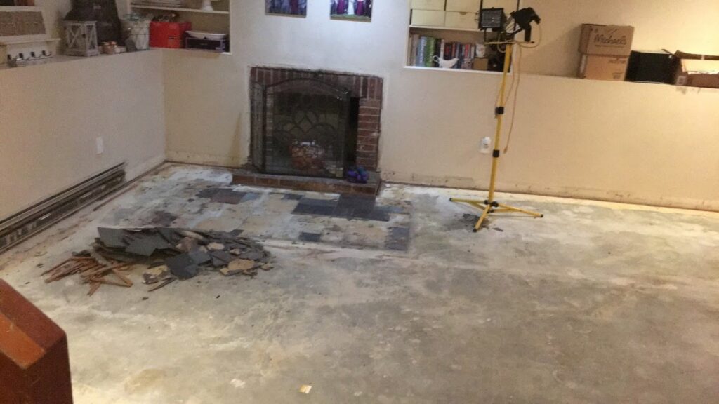 Basement floor removal and renovation preparation in progress, with old tiles cleared by Granite State Handyman & Home Repair in Derry, NH.