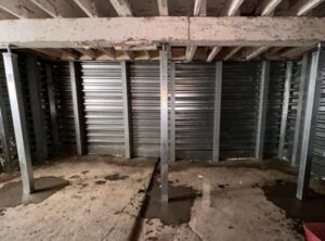 Basement foundation repair with metal support beams and wall panels installed by Woodford Bros., Inc. in Apulia Station, NY