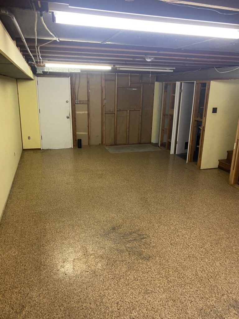 An unfinished basement showing framing and fluorescent lighting, a handyman project by Newhouse Construction St Louis in St. Louis, MO.