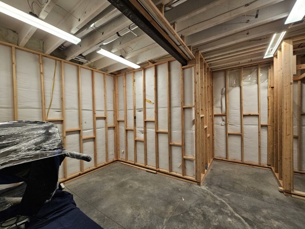 Basement room under construction with wooden framing and insulation being installed by Jedi Bldrs in Colorado Springs, CO.
