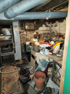 A cluttered basement area near a furnace, filled with boxes and items for junk removal by C&J junk removal llc in Akron, OH.