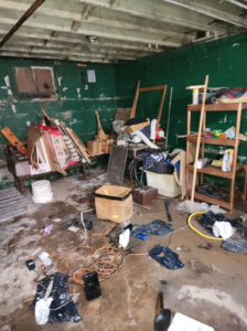 A very messy basement filled with wood, boxes, and debris, requiring junk removal by C&J junk removal llc in Akron, OH.