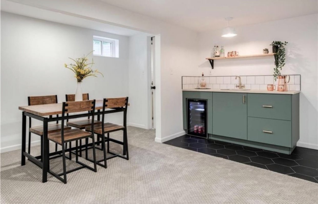 A newly installed basement kitchenette with green cabinets, a sink, and a mini-fridge, part of a renovation by Dogwood Renovation & Design, LLC in Kansas City, MO.