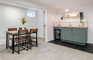 A newly installed basement kitchenette with green cabinets, a sink, and a mini-fridge, part of a renovation by Dogwood Renovation & Design, LLC in Kansas City, MO.