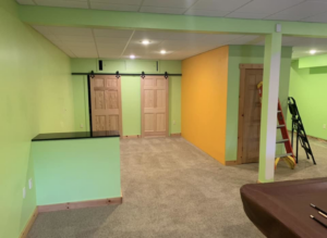 A basement room undergoing remodeling, showing freshly painted walls and barn doors, a project by Berling Remodeling llc in Highland Heights, KY.