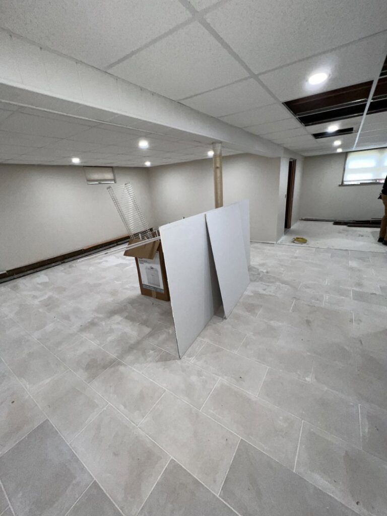 A newly renovated basement by TD Estimating Group LLC in Springfield, MA, featuring new tile flooring and painted walls.