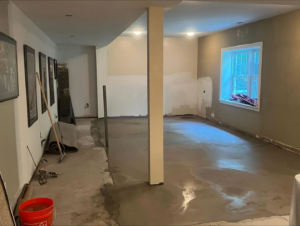 A basement renovation project in progress with a partially finished concrete floor and prepped walls by Home Renovation & Design in Trumbull, CT.