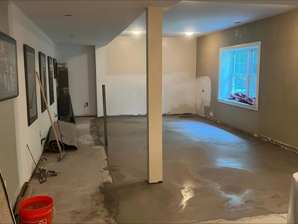 A basement room undergoing renovation with concrete flooring and primed walls by Home Renovation & Design in Trumbull, CT.