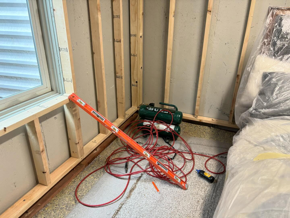 A basement room under construction with new wall framing and tools by iFloor in Westminster, CO.