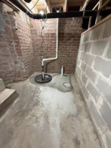 A newly installed sump pump and plumbing in a basement by D&J's Construction Services LLC in Denver, CO.