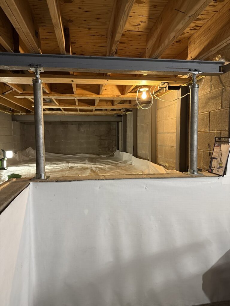 Basement with new support beams and a white liner installed on the floor by The Basement Doctor in Reynoldsburg, OH.