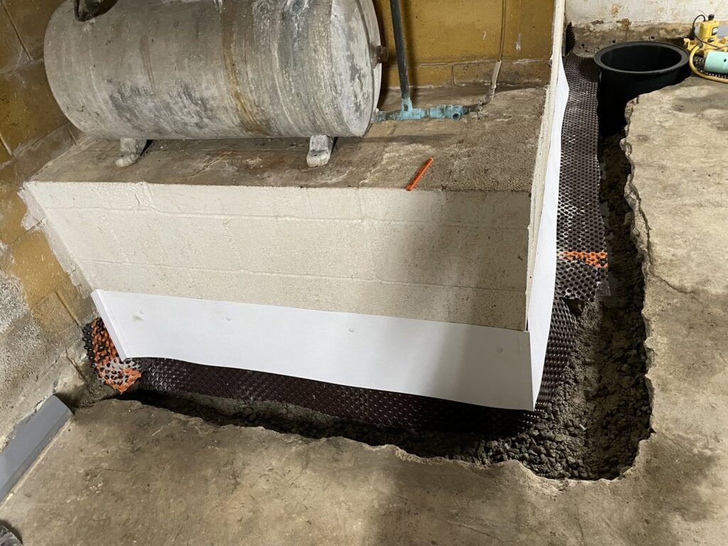 Basement interior with trench, drainage matting, and sump pump pit being installed by Pioneer Basement Solutions in Canton, OH.