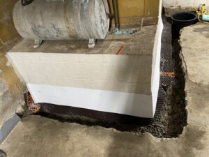 Basement interior with trench, drainage matting, and sump pump pit being installed by Pioneer Basement Solutions in Canton, OH.