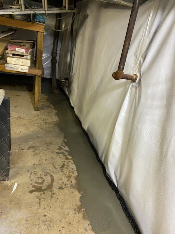 A basement waterproofing liner system installed with a concrete trench by ARK Basement Services - Erie, PA