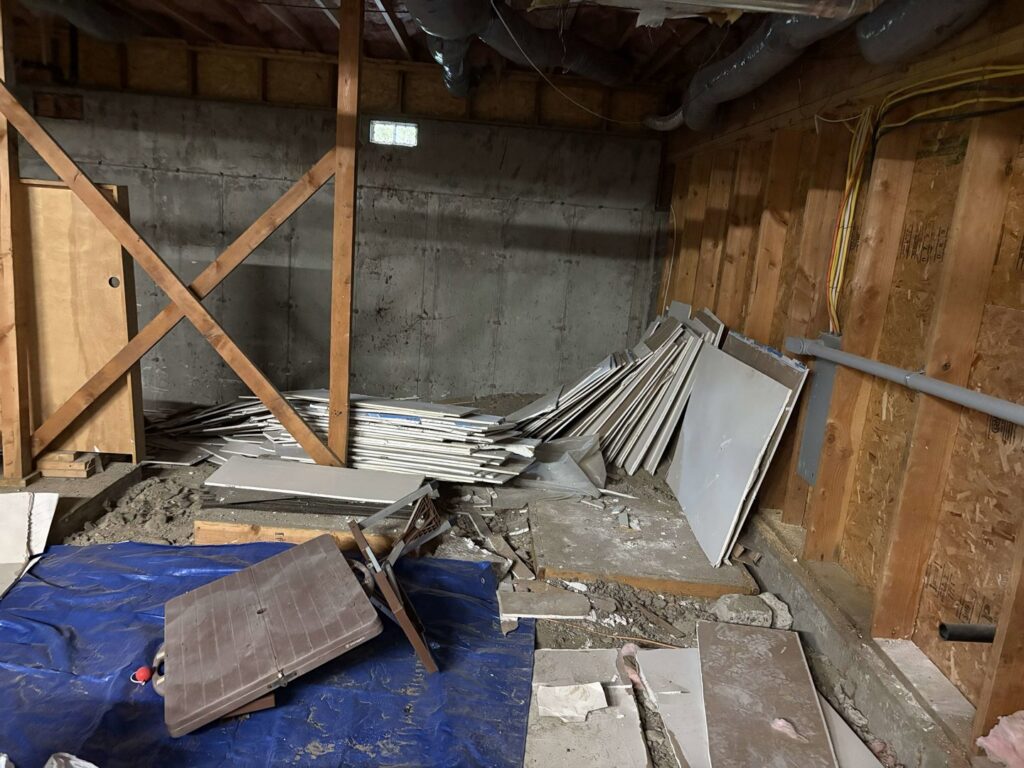 A basement filled with piles of drywall, wood, and construction debris, ready for removal by Down and Dirty Junk Removal in Tacoma, WA.