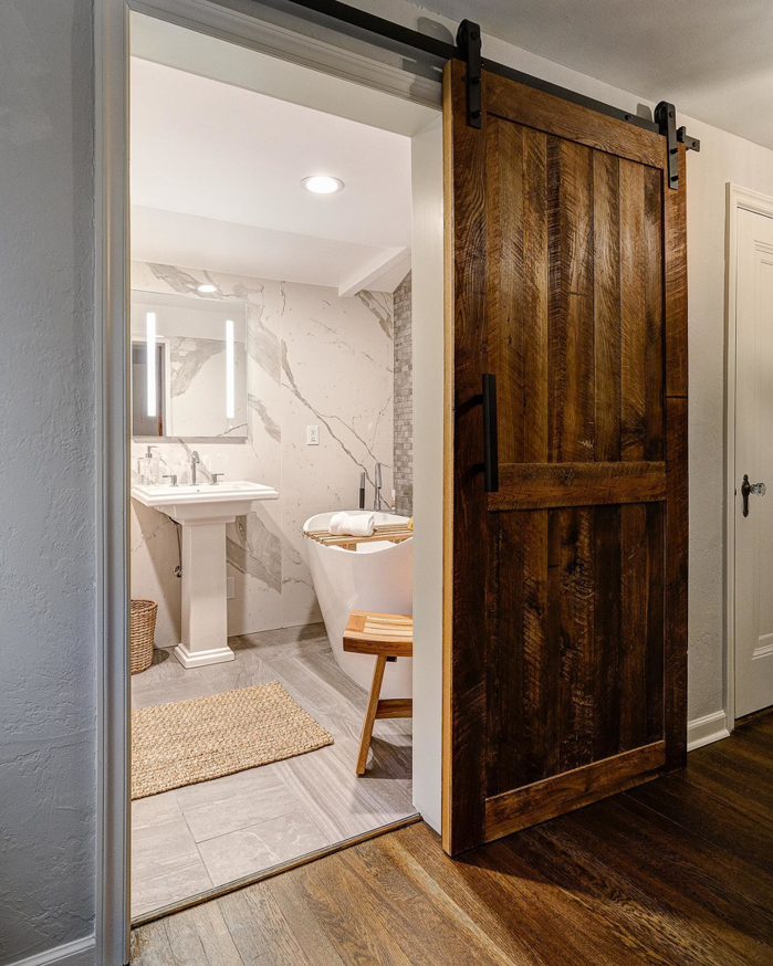 A newly installed barn door leading to a remodeled bathroom by Scott Hall Remodeling in Columbus, OH.