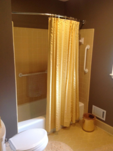 A bathroom with a bathtub, yellow tiles, and installed grab bars by Kingdom Advance Construction in Louisville, KY