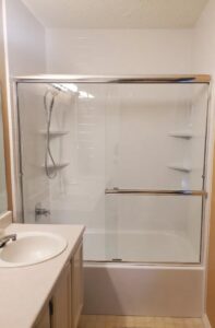 A completed bathroom update featuring a bathtub with new glass sliding shower doors installed by McCollister Contracting LLC in New Castle, DE.