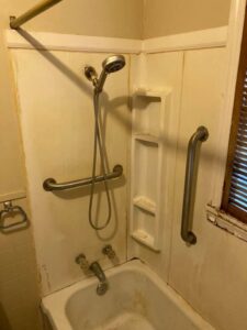 A bathroom before remodeling, showing a bathtub and shower area with existing grab bars, ready for renovation by AON Construction and Remodeling LLC in Wichita, KS.
