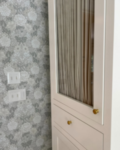 Detail of bathroom cabinet, decorative wallpaper, and electrical outlets by Kevin Cradock Builders in Boston, MA.