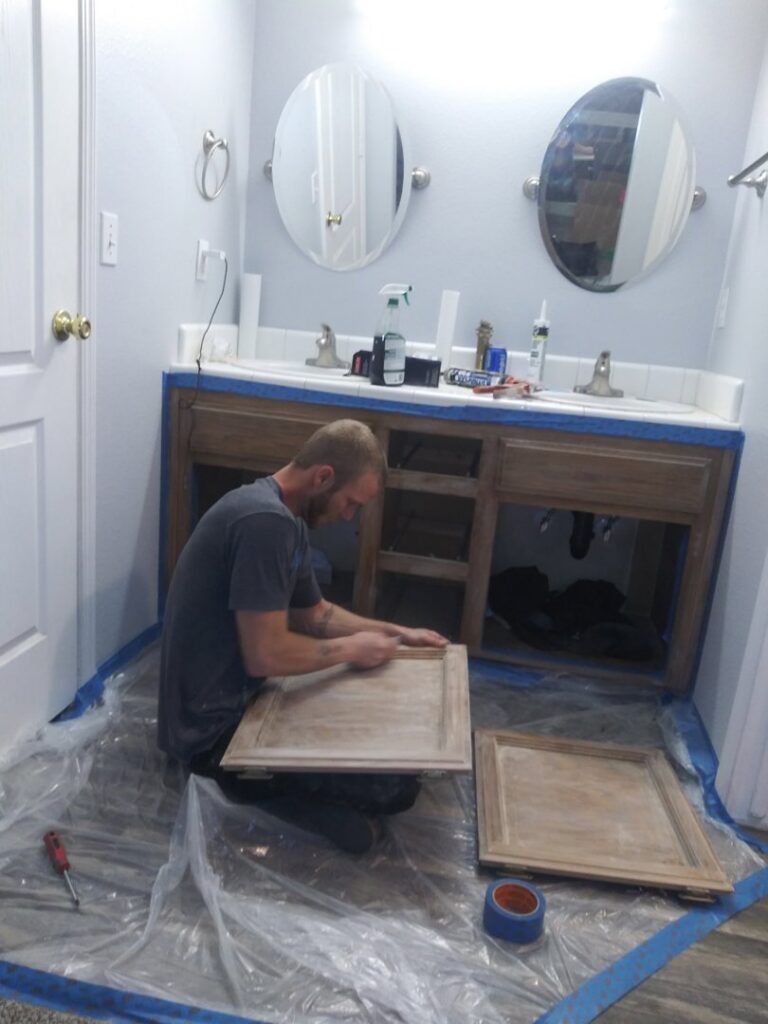 A contractor refinishing bathroom cabinet doors during a renovation by Red Gator Maintenance in Fresno, CA.
