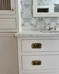 Detailed view of bathroom cabinetry with brass hardware and marble countertop by Kevin Cradock Builders in Boston, MA.