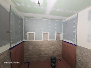 Early stage of a bathroom construction project showing drywall installation and initial tiling by Torres Services in Anchorage, AK.