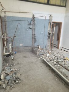Wide view of a bathroom demolition with debris and exposed pipes by Green Man's Contracting & Landscaping LLC in West Hartford, CT.