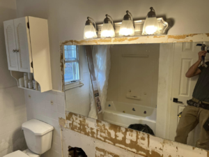 Bathroom demolition with mirror removal in progress, showing renovation work by JTL Contracting Services LLC in Inver Grove Heights, MN