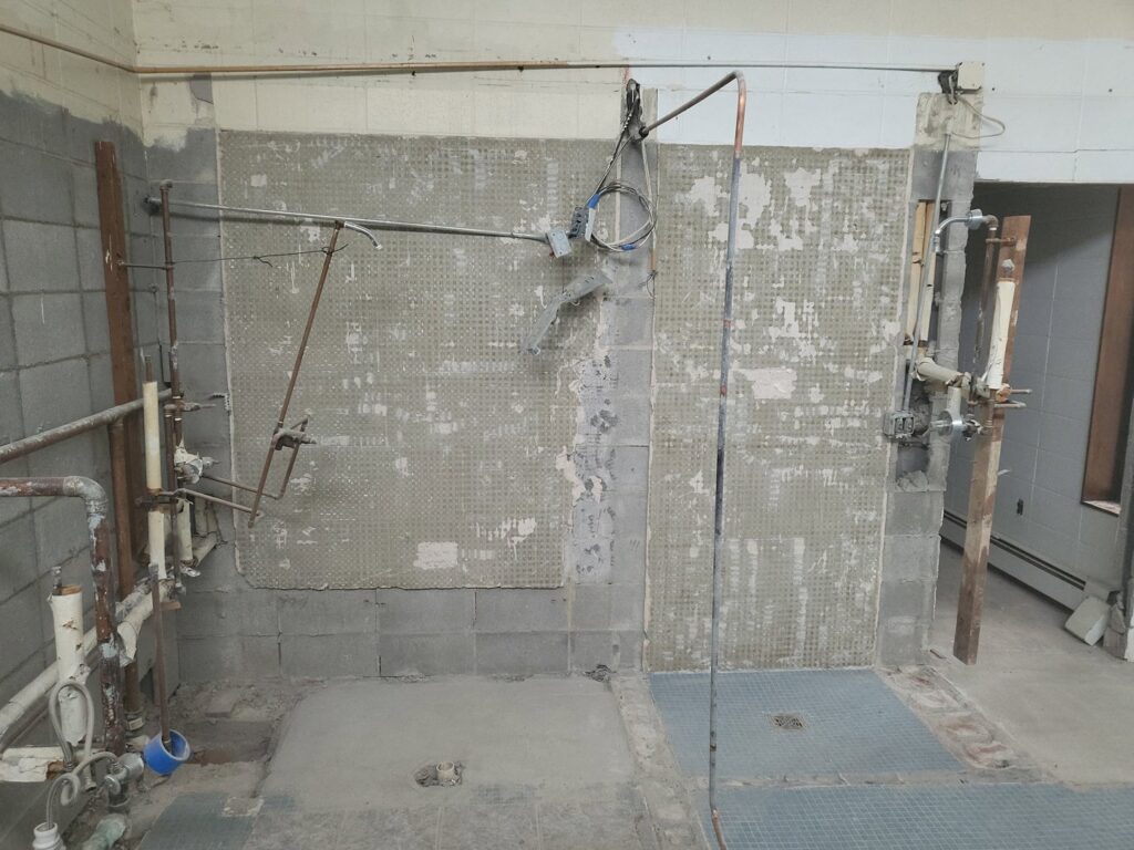 Bathroom or utility room undergoing demolition with exposed pipes by Green Man's Contracting & Landscaping LLC in West Hartford, CT.