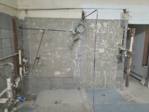 Bathroom or utility room undergoing demolition with exposed pipes by Green Man's Contracting & Landscaping LLC in West Hartford, CT.