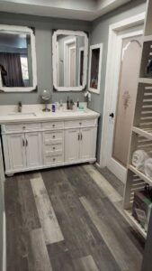 A renovated bathroom featuring a double vanity, mirrors, and new vinyl plank flooring, completed by Go Joe Handyman in Overland Park, KS.