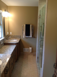 A renovated bathroom with a double vanity, granite countertops, and glass shower by Kingdom Advance Construction in Louisville, KY
