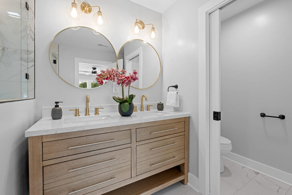 A bathroom featuring a double vanity with gold fixtures and round mirrors installed by Heroic Builders LLC in Greenville, SC.