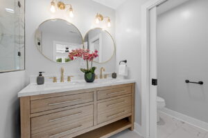 A bathroom featuring a double vanity with gold fixtures and round mirrors installed by Heroic Builders LLC in Greenville, SC.