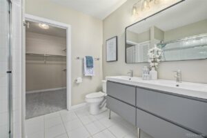 A renovated bathroom featuring a modern double vanity, large mirror, and toilet by RAW Renovation in Denver, CO.
