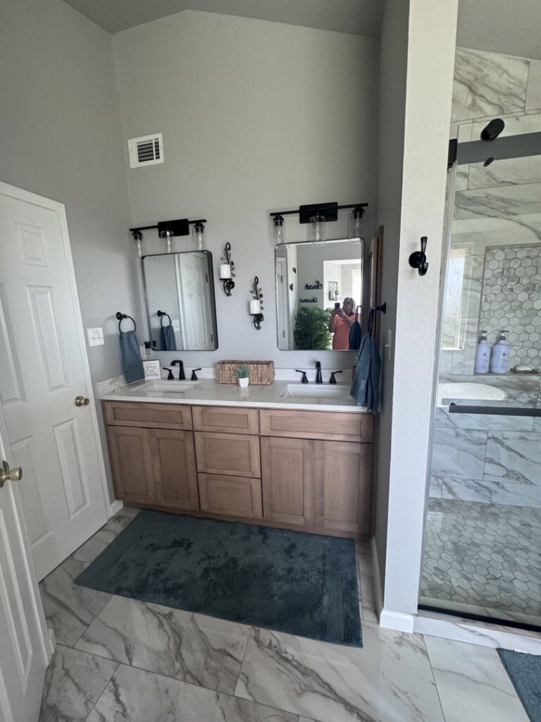 A renovated bathroom featuring a double vanity with modern mirrors and lighting by A&R Home Improvements in El Paso, TX